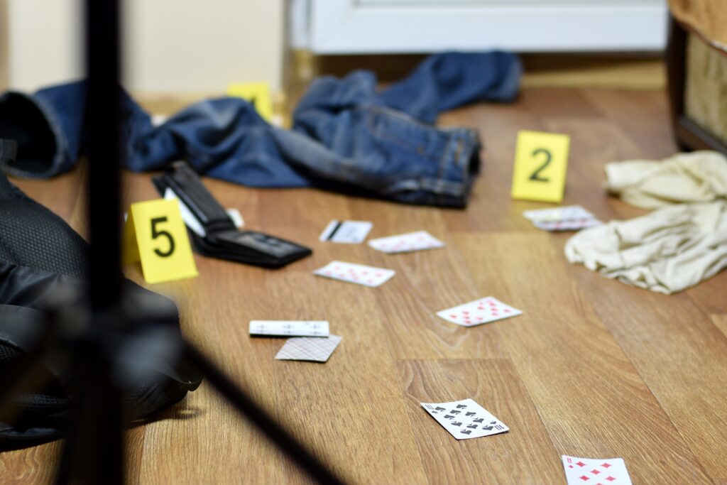 Crime scene investigation - numbering of evidences after the murder in the apartment. A lot of playing cards, wallet and clothes with evidence markers close up