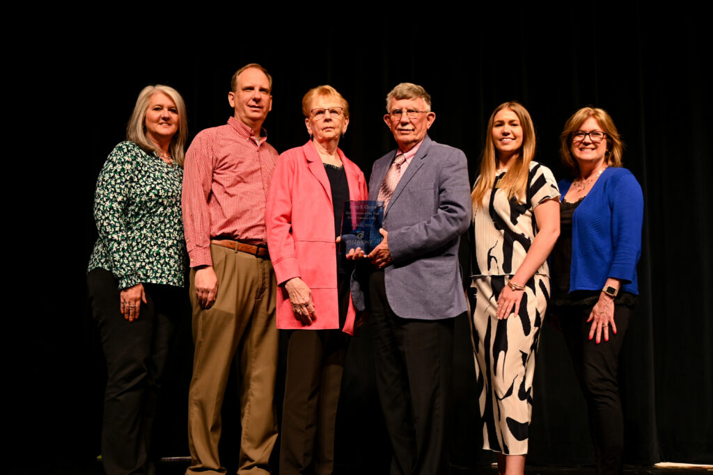Jimmy Clayton holding award with family and two PCC staff members